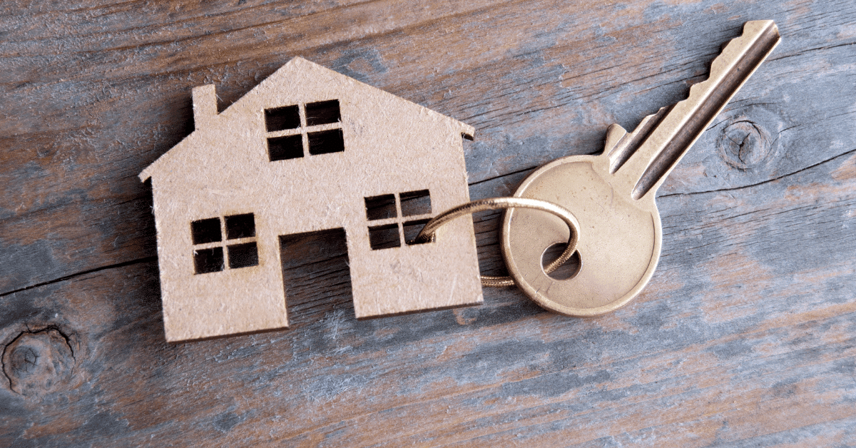 Close-up of a house key on a wooden table, symbolizing home ownership and new housing opportunities.